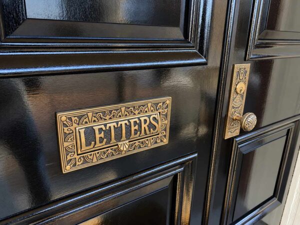 Decorative brass mail slot and door hardware on recreated historic front doors